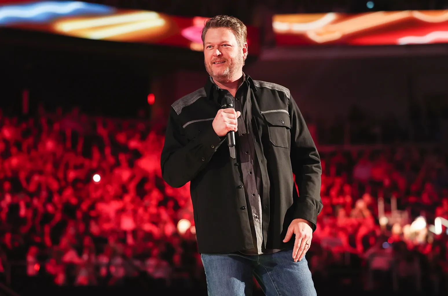 Singer speaking to a red-lit arena crowd