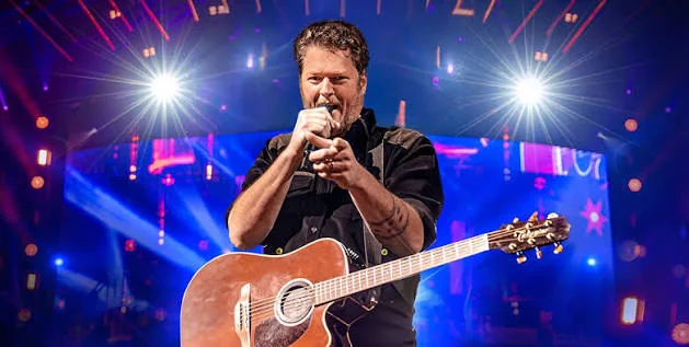 Country singer performing with acoustic guitar under blue lights